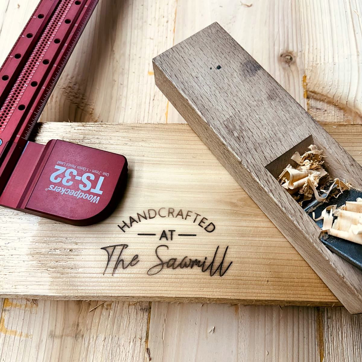 Handcrafted at The Sawmill stamp burned into a board, with a Woodpeckers square and a hand plane